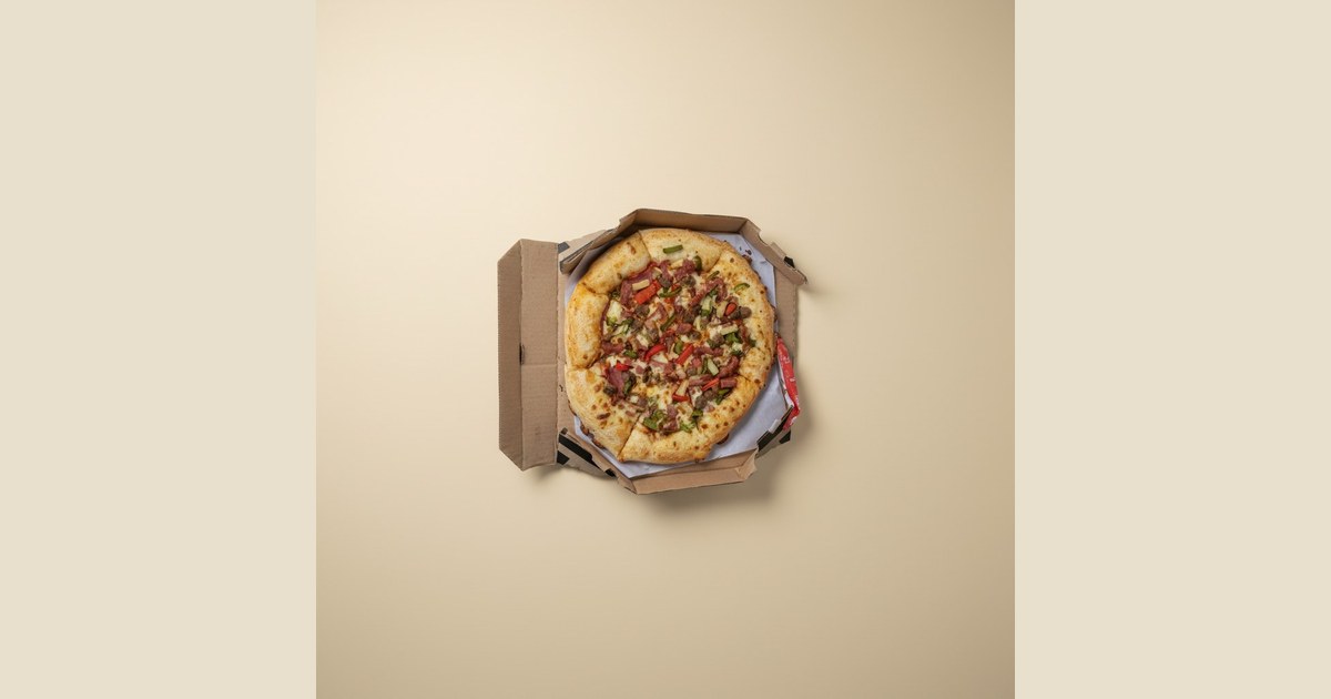 Hot pizza with meat and vegetable toppings in a box.